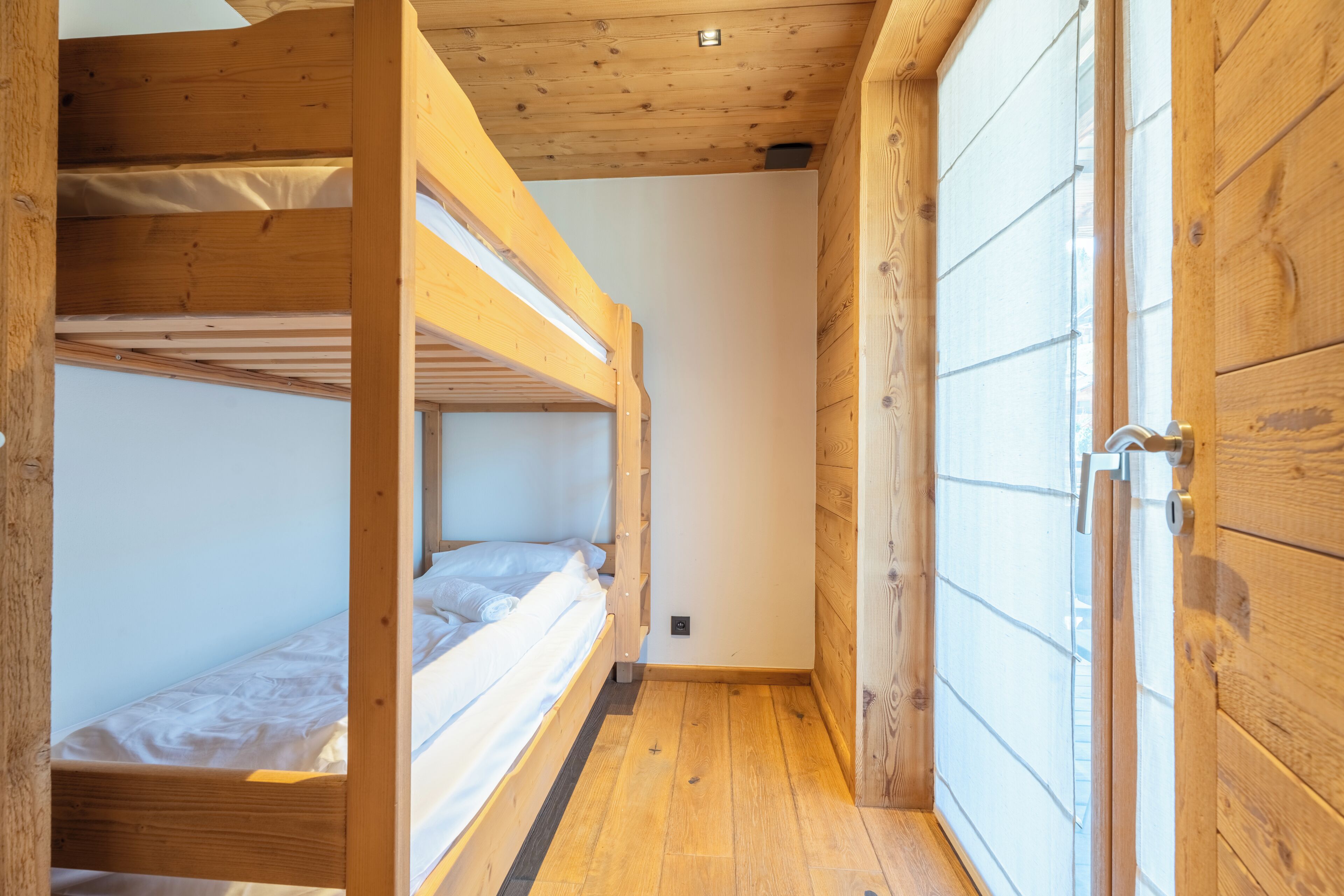 A wooden interior with bunk beds and a wardrobe.