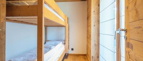 A wooden interior with bunk beds and a wardrobe.