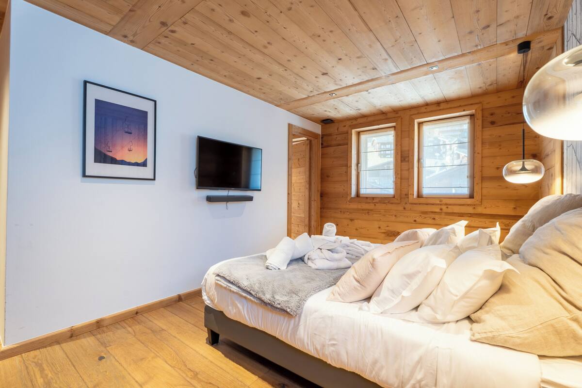 Huoneessa on sänky, televisio ja seinällä oleva kehystetty kuva.