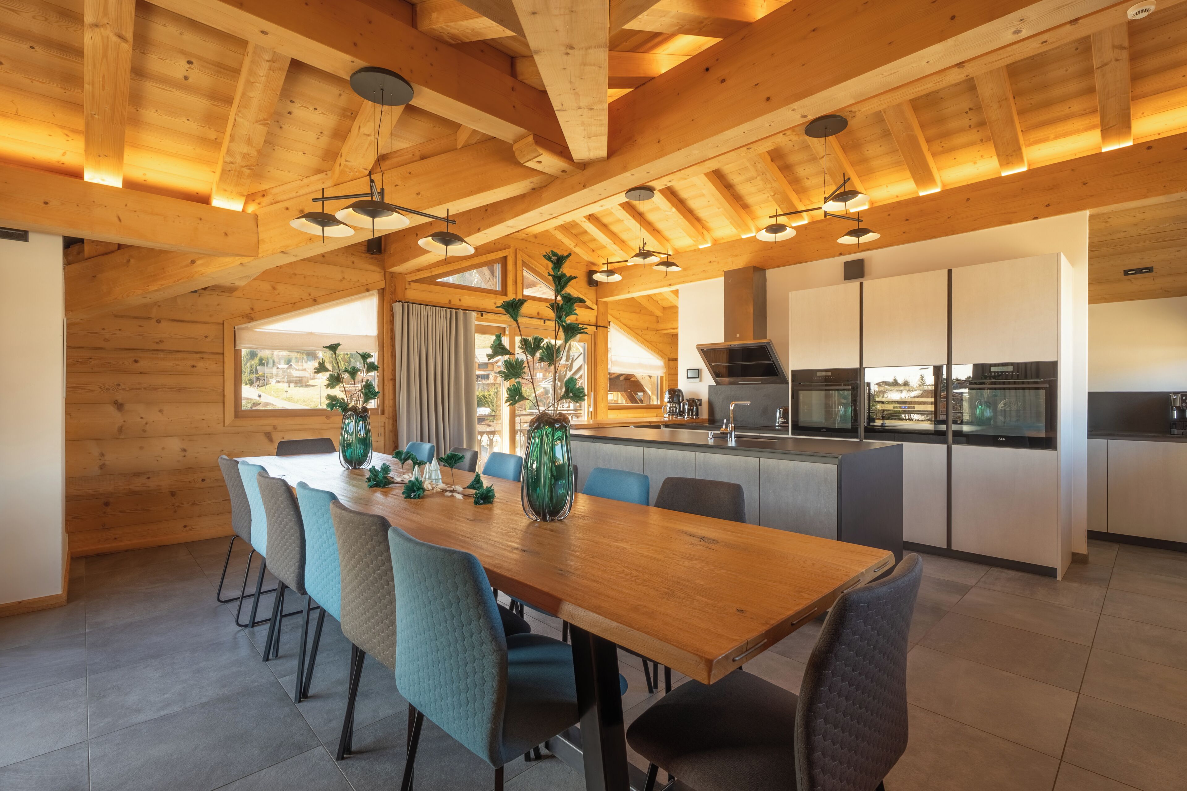 Eine moderne Küche mit integrierten Geräten, ein Essbereich mit Holztisch und -stühlen sowie ein Blick ins Freie.