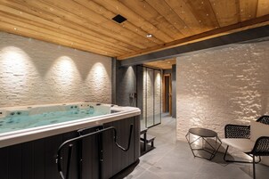 Un área de spa moderna con un jacuzzi, asientos y techo de madera.