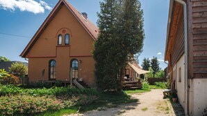 Une maison traditionnelle avec un toit en pente, une véranda en bois et un jardin fleuri.