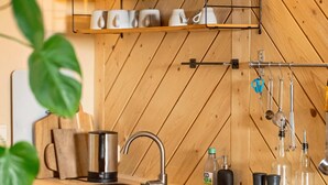 Une cuisine avec des murs en bois, un évier en acier inoxydable et un étendoir suspendu où sont rangés les ustensiles de cuisine.