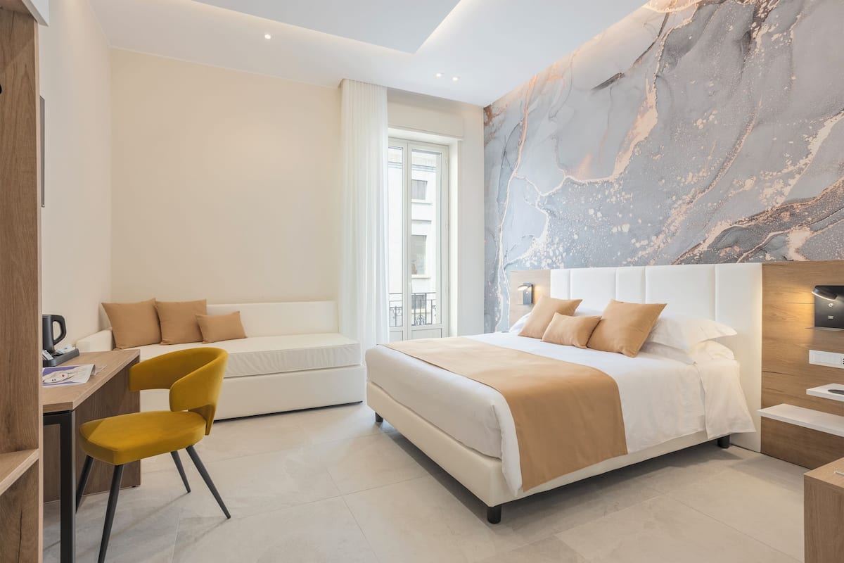 Ein modernes Hotelzimmer mit einem Bett, einem Schreibtisch, einem Stuhl und einer großen Marmorwand.