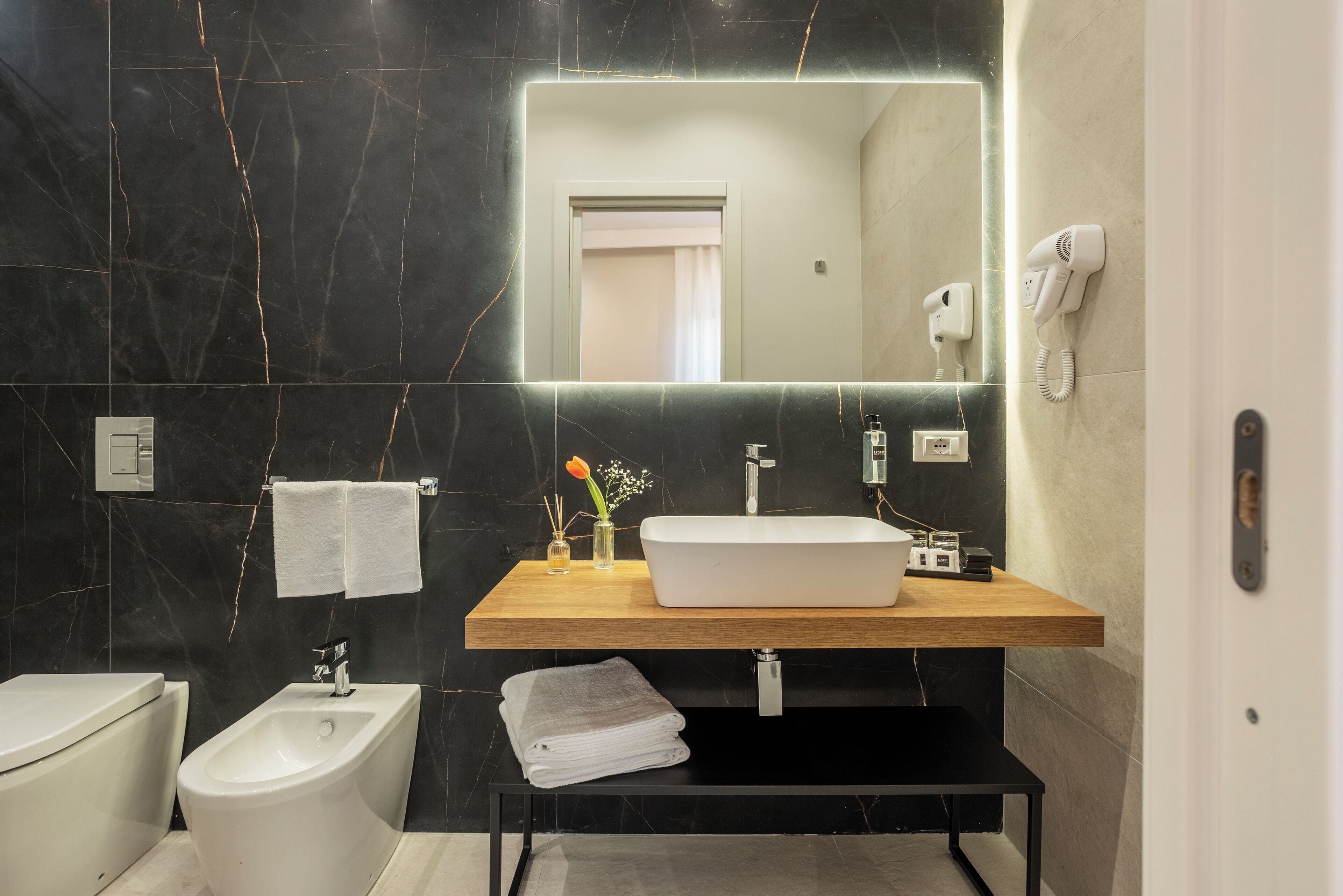 A modern bathroom with a vanity, bidet, and a large mirror.