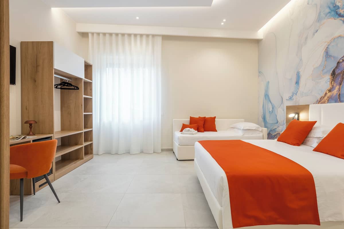 Ein modernes Hotelzimmer mit Bett, Schreibtisch, Stuhl, Kleiderschrank und einem großen abstrakten Gemälde an der Wand.