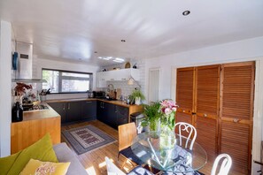 A modern kitchen with a dining area, wooden cabinets, and a large window. - Modern 2BD Flat w/ Decked Terrace, Dulwich (Greater London)
