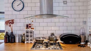 Una cocina moderna con estufa a gas, campana extractora de acero inoxidable y un reloj en la pared.