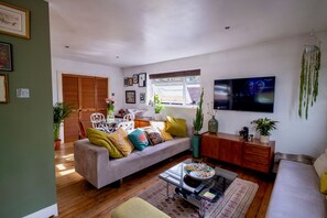 A living room with a sofa, coffee table, and a television mounted on the wall. - Modern 2BD Flat w/ Decked Terrace, Dulwich (Greater London)