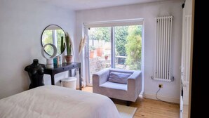 Un dormitorio con una cama, una silla, un escritorio con espejo y un radiador.
