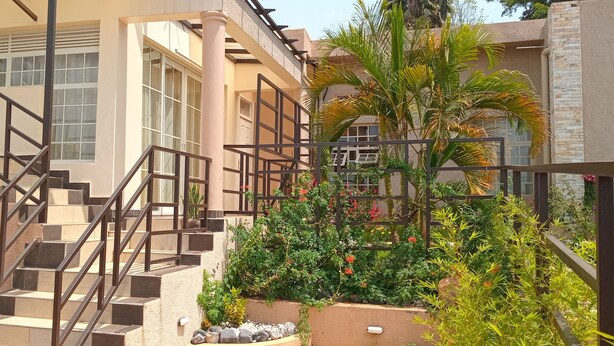 Un edificio de varios pisos con escaleras, plantas al aire libre y un muro de piedra.