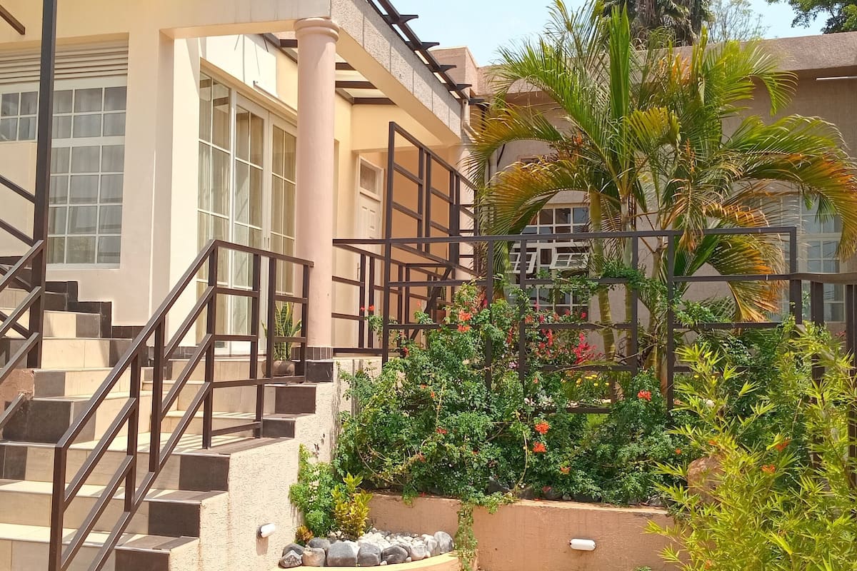 Un edificio de varios pisos con escaleras, plantas al aire libre y un muro de piedra.