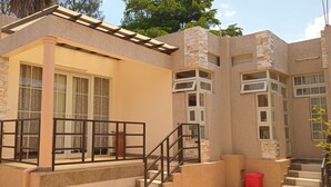 Una casa moderna con fachada de piedra, ventanas amplias y un balcón con barandilla de metal.