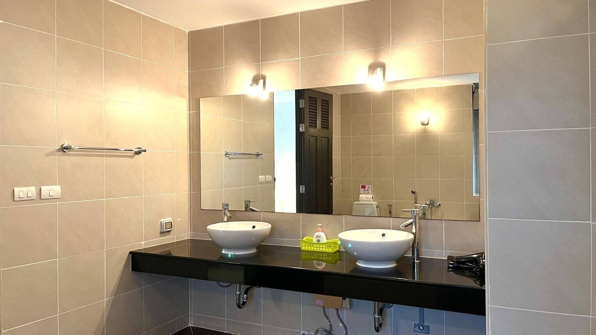 Un baño moderno con dos lavamanos, un espejo grande y un perchero para toallas.
