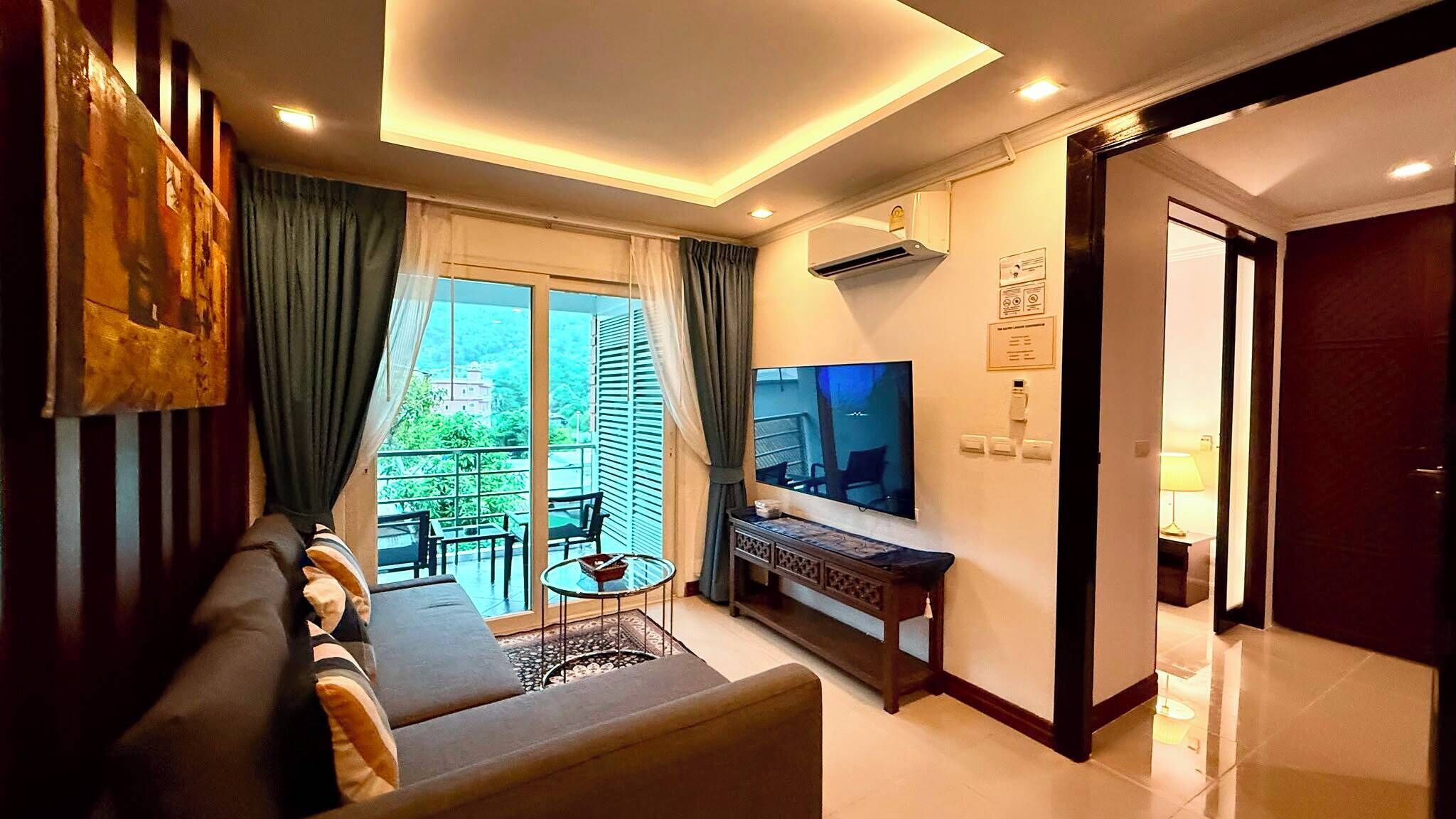 A modern living room with a sofa, TV, and balcony.