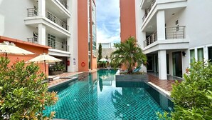 Un hôtel moderne doté d’une piscine centrale, entouré d’une végétation luxuriante et agrémenté d’espaces de détente en plein air.