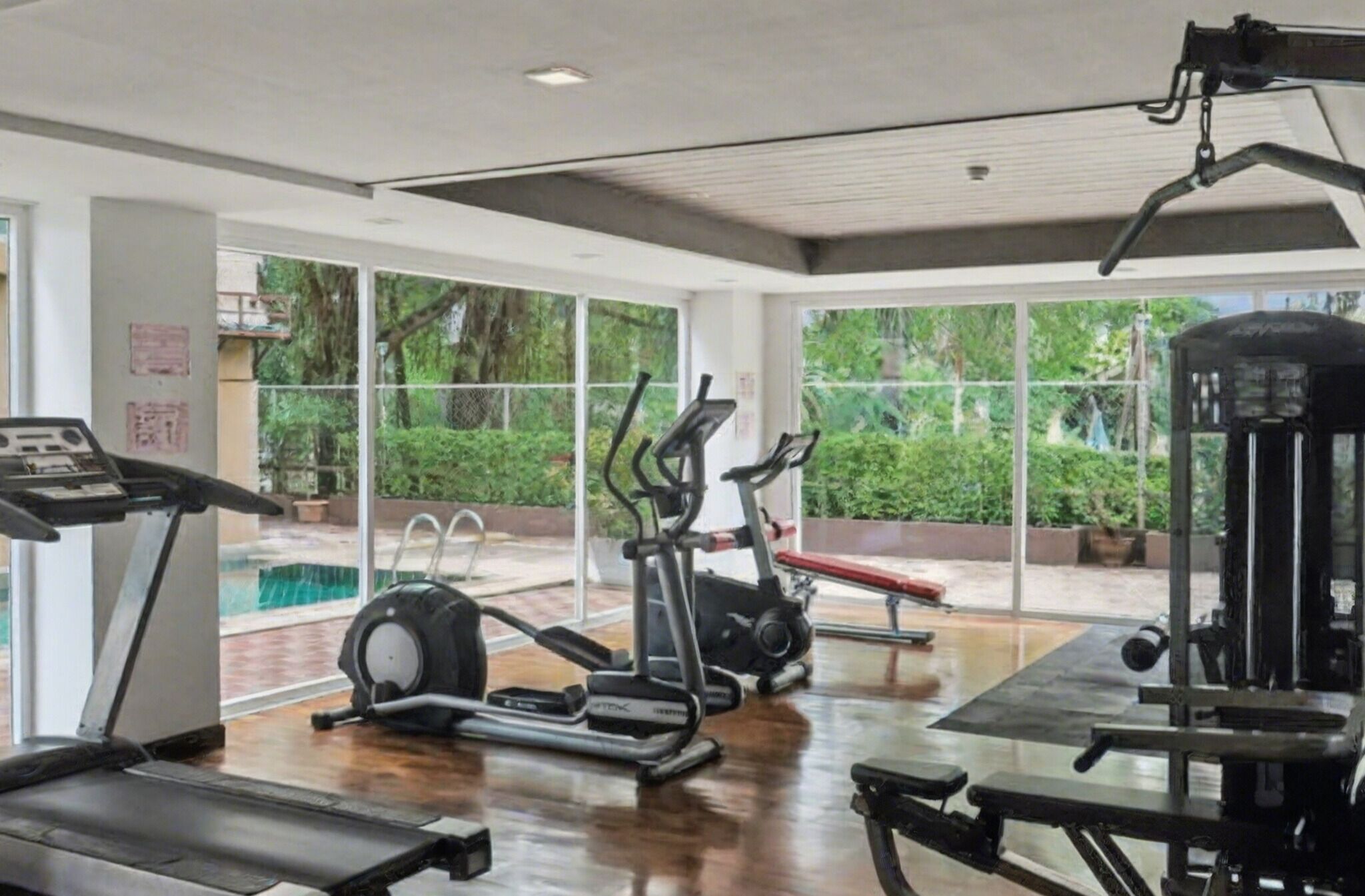 Une salle de sport équipée de machines de cardio, de matériel de musculation et d’un banc.