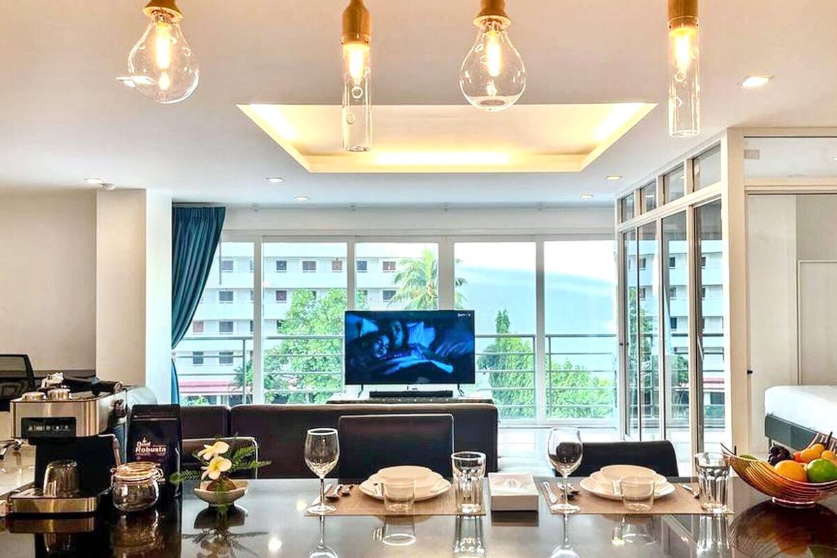 A hotel room with a dining area, a television, and a large window with a view.