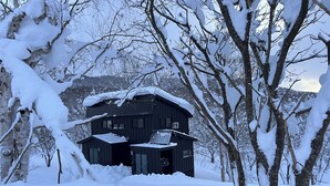 A dark wooden cabin surrounded by snow-covered trees. - Niseko Town, Toyosato A near Hirafu, Niseko village and 30' Risutsu (Niseko-cho)