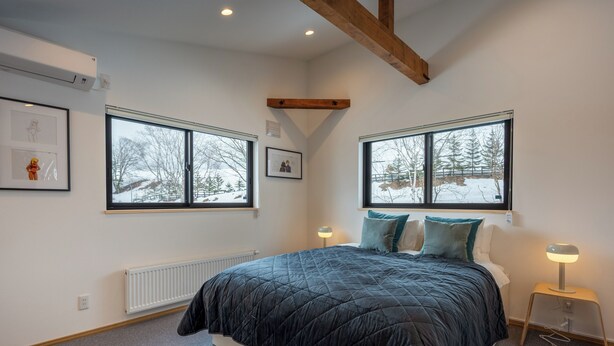 A bedroom with a large bed, two windows, a radiator, and a bedside table with a lamp. - Niseko Town, Toyosato A near Hirafu, Niseko village and 30' Risutsu (Niseko-cho)