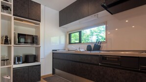 A modern kitchen with dark cabinetry, a built-in microwave, and a window providing natural light. - Niseko Town, Toyosato A near Hirafu, Niseko village and 30' Risutsu (Niseko-cho)