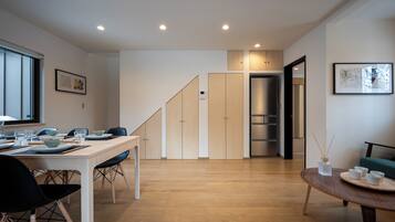 A modern kitchen with wooden cabinets, a dining table set with plates and glasses, and a staircase leading to another room.