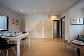 A modern kitchen with wooden cabinets, a dining table set with plates and glasses, and a staircase leading to another room. - Niseko Town, Toyosato A near Hirafu, Niseko village and 30' Risutsu (Niseko-cho)