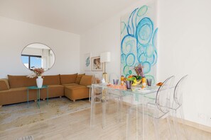 A modern living room with a brown sofa, a round mirror, a glass coffee table, and a dining area with clear chairs and a glass table. - 2 bedrooms, terrace, peaceful ocean view, 6-minute walk to the beach, A2B262 (Cannes)