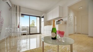 Un salón moderno con una mesa de vidrio, una botella de champán y una copa rosa.