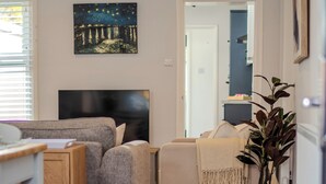 A modern living room with a sofa, a television, and a painting on the wall. - Stylish 2-bed house ideal for business & family stays, garden, free parking. (Southampton)