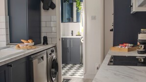 A modern kitchen with dark cabinetry, a built-in washing machine, and a marble countertop. - Stylish 2-bed house ideal for business & family stays, garden, free parking. (Southampton)