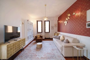 Un salon comprenant un téléviseur, un canapé, un pouf et un mur décoratif.
