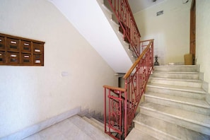 Un escalier avec une rampe rouge et une main courante en bois, menant à l’étage supérieur.