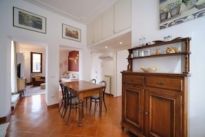 Un coin repas avec une table et des chaises en bois, un meuble contenant des ustensiles de cuisine et un tableau accroché au mur.