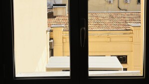 A view through a window with a door, revealing a building with multiple windows and a tiled roof.