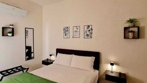 A bedroom with a bed, bedside tables, a mirror, and wall-mounted artwork.