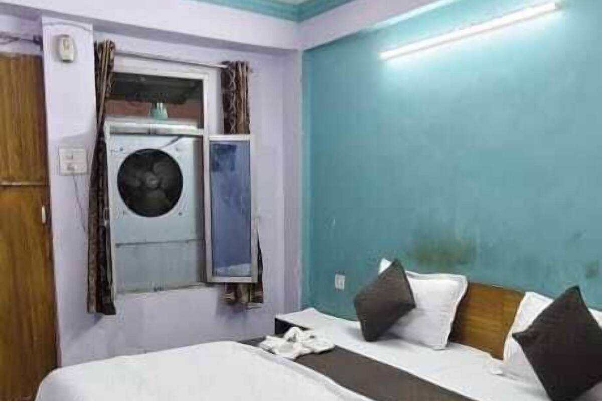 Hotellihuone, jossa on sänky, pesukone ja kattotuuletin.