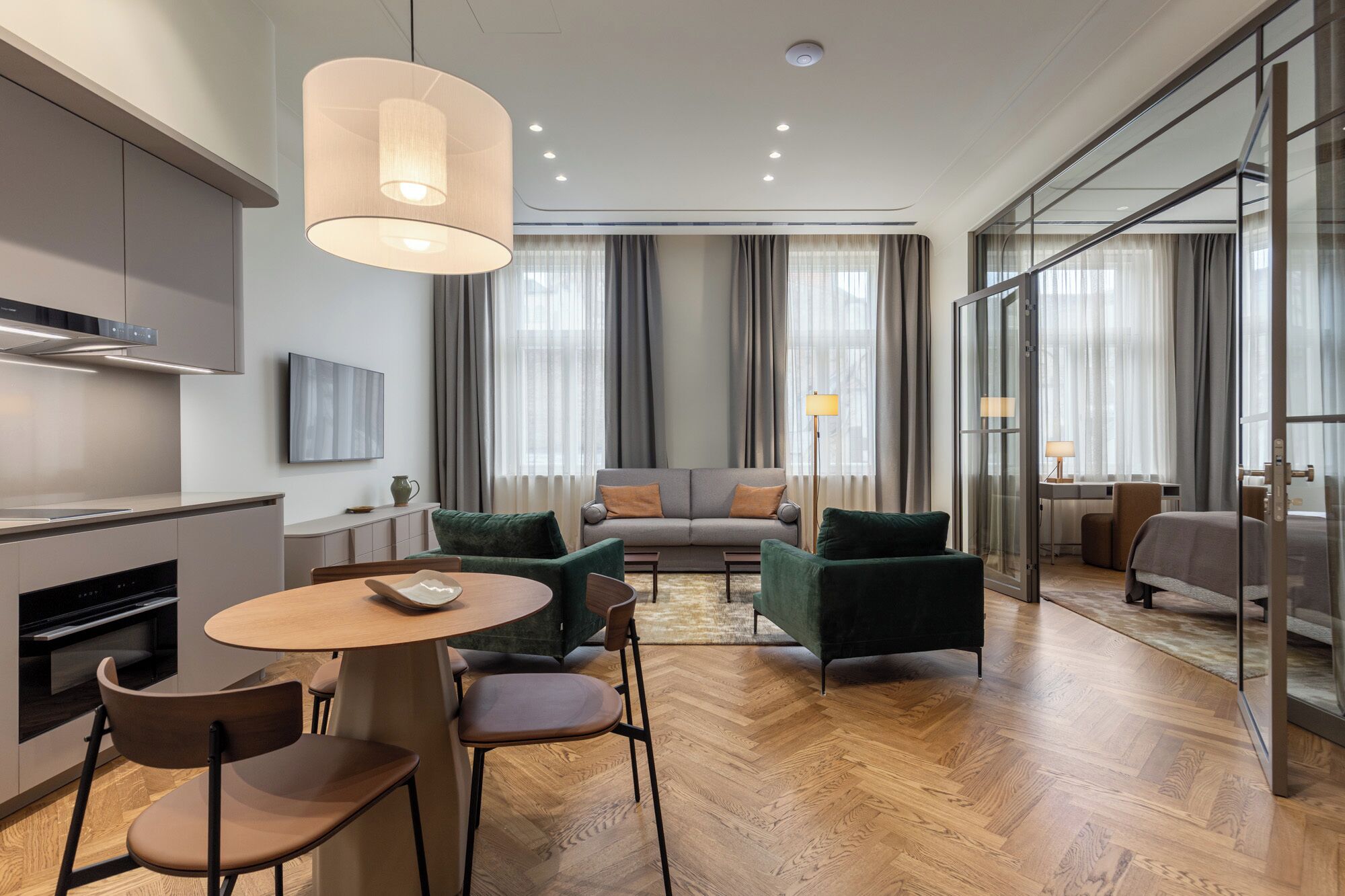 A modern living room with a sofa, chairs, a dining table, and a kitchen area.