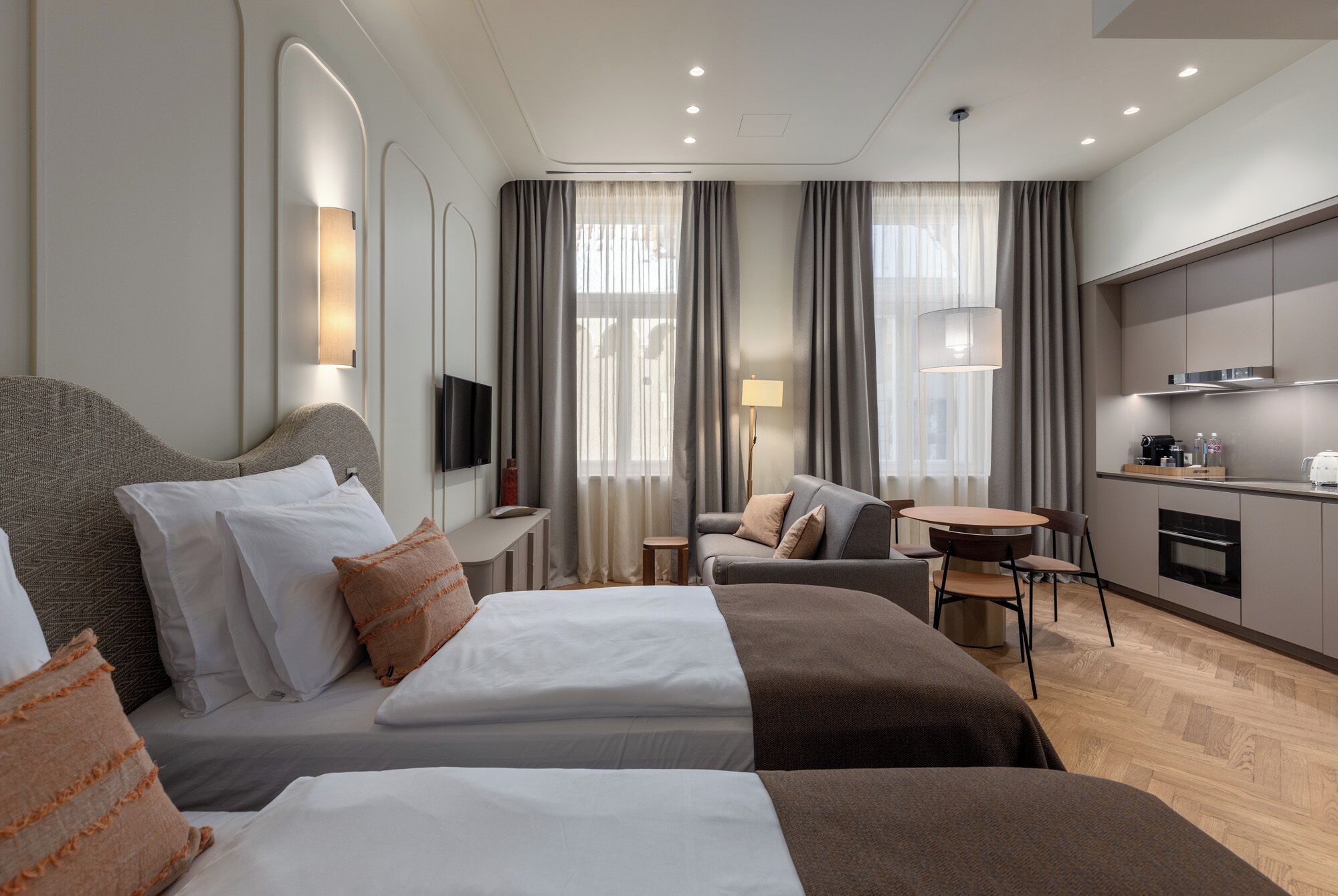 Una habitación de hotel con cama, sofá, escritorio, televisor y kitchenette.