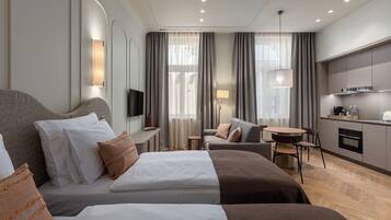 Una habitación de hotel con cama, sofá, escritorio, televisor y kitchenette.