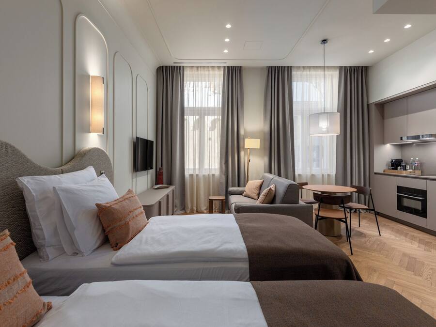 Una habitación de hotel con cama, sofá, escritorio, televisor y kitchenette.