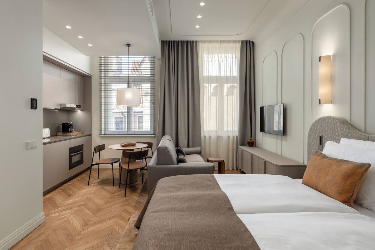 Une chambre d’hôtel moderne équipée d’un lit, d’un canapé, d’une petite table à manger et d’un téléviseur.