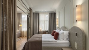 Una habitación de hotel moderna con una cama grande, una mesita de noche, un escritorio con lámpara y vistas amplias por una ventana grande.