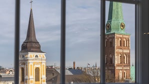 Dos torres de iglesia destacadas con agujas y relojes, vistas a través de una ventana con diseño de cuadrícula.