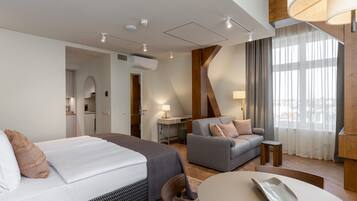 Una habitación de hotel moderna con cama, sofá, mesa y vistas a la ciudad a través de amplias ventanas.