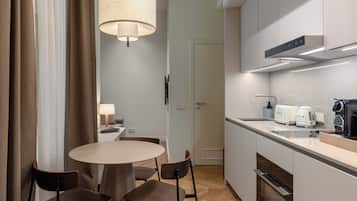 A modern kitchen with a round dining table, chairs, a hanging light fixture, and built-in appliances.