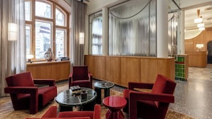 Vestíbulo de hotel con zona de estar, ventanas amplias y mostrador de recepción.