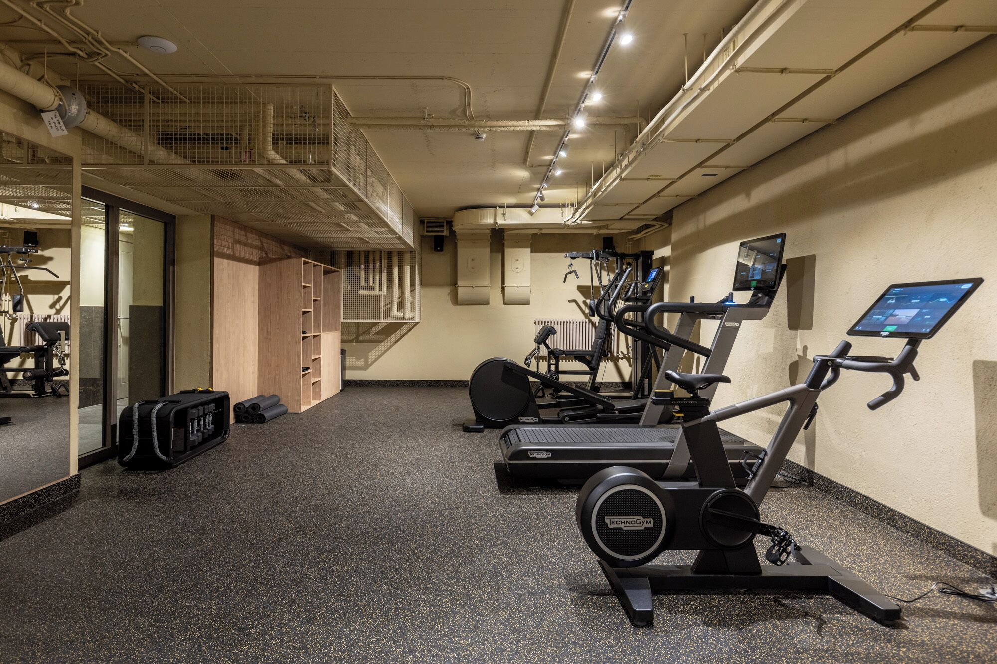 Un gimnasio con equipo de ejercicio, una escalera y un muro con espejos.