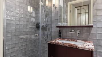 A modern bathroom with a glass-enclosed shower, a marble sink, and a large mirror.