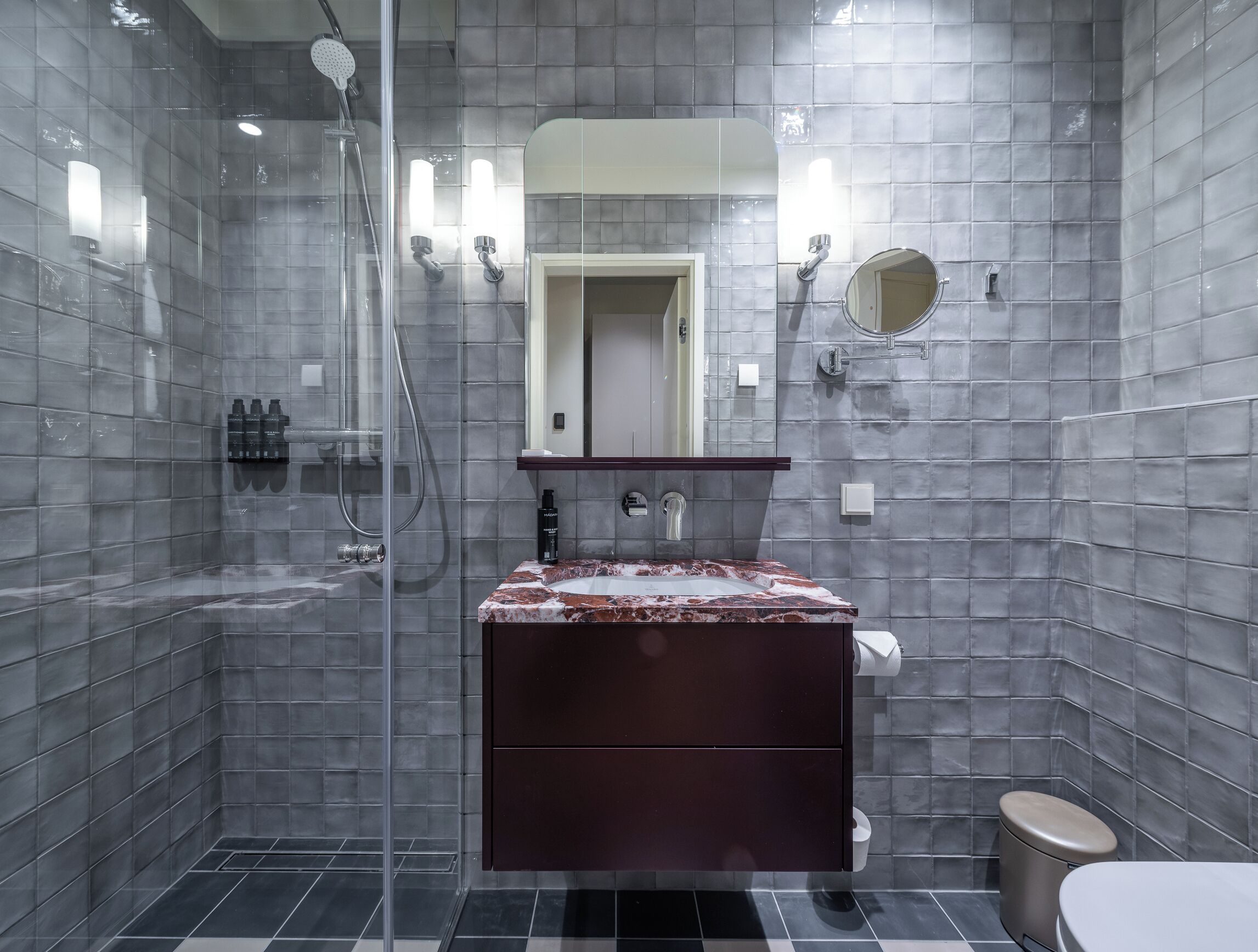 Ein modernes Badezimmer mit einer Duschkabine aus Glas, einem Marmorwaschtisch und einem dunklen Waschtischschrank.